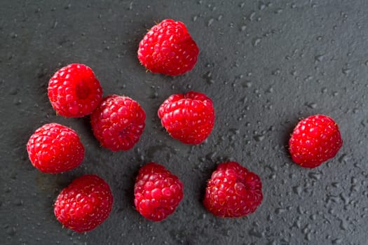 berries raspberry on black background macro closeup with fresh water drops