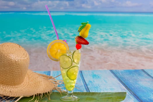 Lemon lime cocktail mojito on tropical turquoise beach on blue wood