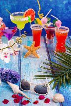colorful mixed cocktails in tropical blue wood flowers starfish and sunglasses