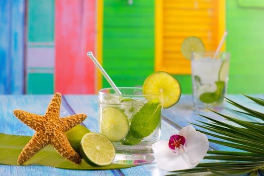 Cuban Mojito cocktail in tropical colorful house on blue wood with flowers and starfish