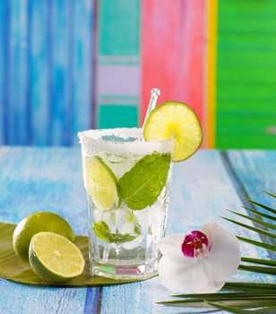 Cuban Mojito cocktail in tropical colorful house on blue wood with flowers and starfish