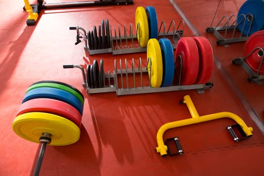 Crossfit fitness gym weight lifting bar colorful equipment on red floor