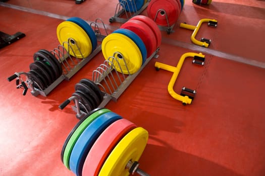 Crossfit fitness gym weight lifting bar colorful equipment on red floor