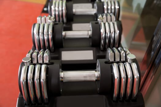Adjustable weight dumbbells in a row with selective focus in foreground
