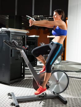 Aerobics spinning monitor trainer woman stretching exercises after workout at gym