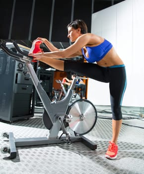 Aerobics spinning monitor trainer woman stretching exercises after workout at gym