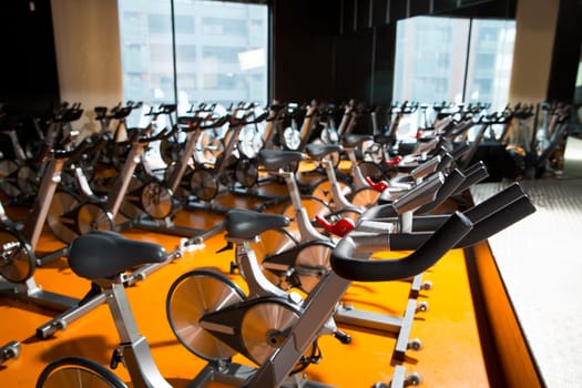 Aerobics spinning exercise bikes gym room with many in a row