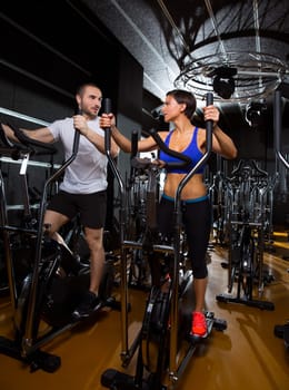 elliptical walker trainer man and woman at black gym training aerobics exercise