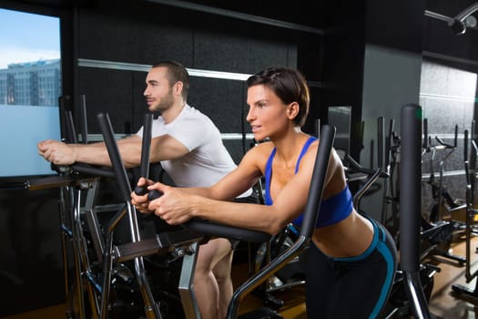 elliptical walker trainer man and woman at black gym training aerobics exercise