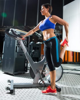 Aerobics spinning monitor trainer woman stretching exercises after workout at gym