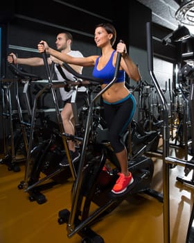 elliptical walker trainer man and woman at black gym training aerobics exercise