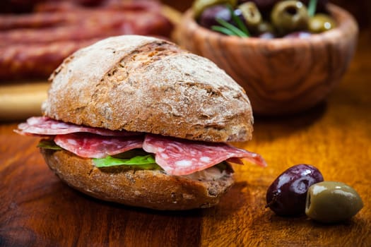 Whole grain sandwich with Italian salami, goat cheese and fresh olives