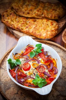 Baked feta cheese on vegetables and olive bread