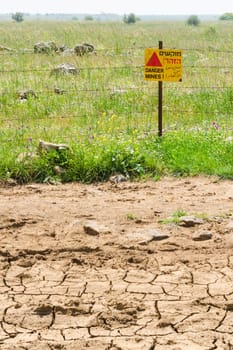 Flowered green minefield fenced barbed wire with warning sign