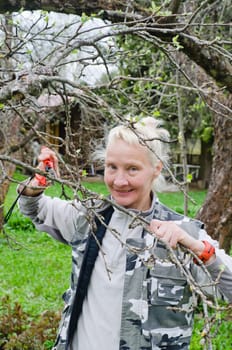 Woman cuts a branch at an Apple-tree, a spring in the garden