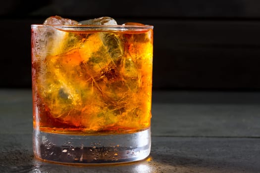 Whiskey whisky on the rocks on glass over gray black background