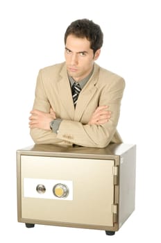 Young male businessman in light suit stands with his arms folded behind a locked safe, isolated against white background.