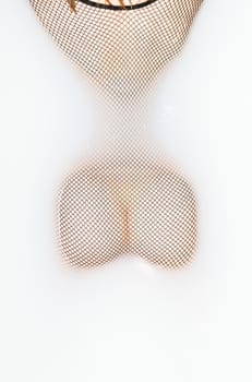 Young woman lying in the Bathtub and wearing a sexy fishnet bodystocking. Showing her backside and her butts.