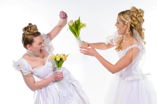 Two young brides in white wedding dresses fight against each other and beat with flowers