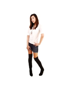 A very tall young Chinese woman standing for white background in black long boots and shorts.