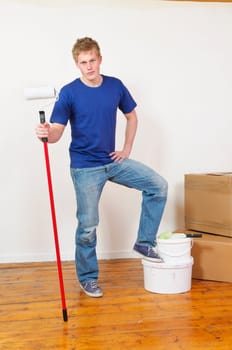 Young man in a T-shirt paints the walls of his first apartment in bright colors.