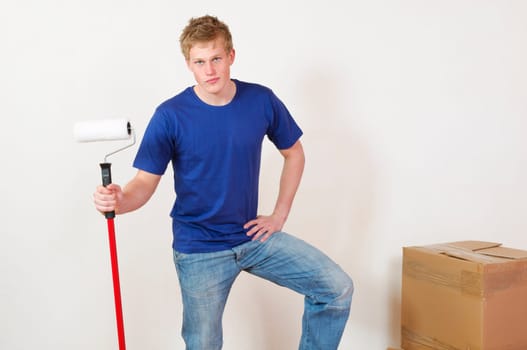 Young man in a T-shirt paints the walls of his first apartment in bright colors.