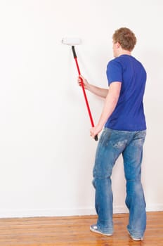 Young man in a T-shirt paints the walls of his first apartment in bright colors.