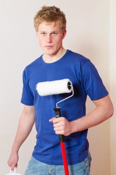 Young man in a T-shirt paints the walls of his first apartment in bright colors.