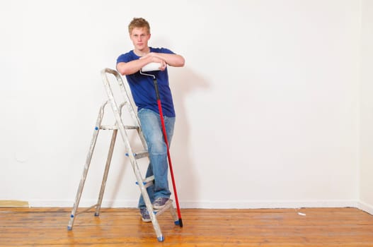 Young man in a T-shirt paints the walls of his first apartment in bright colors.