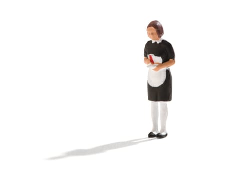 Miniature figure of a maid or hired help in a black uniform with white apron over a white background with copy space