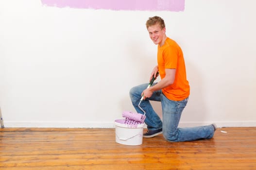 Young man in a T-shirt paints the walls of his first apartment in bright colors.