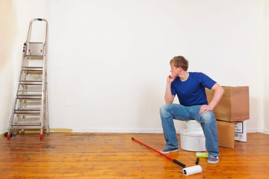 Young man in a T-shirt paints the walls of his first apartment in bright colors.