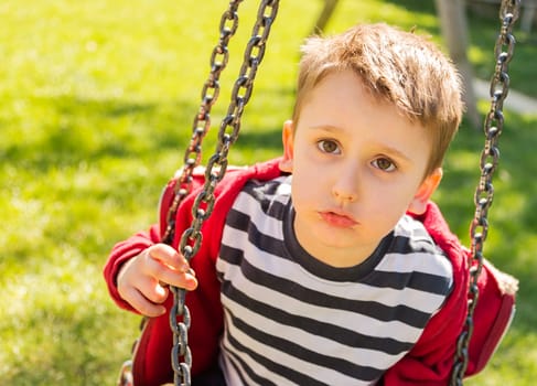 A child playing in the playground to 'swing on a sunny day.