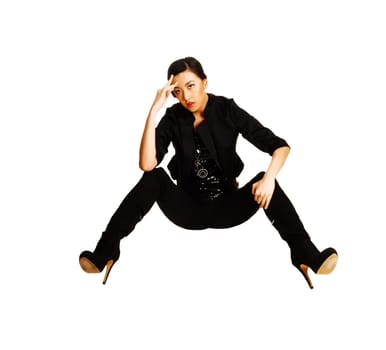 A tall slim young chinese woman in a black blouse and jacket and black tights  with long black boots sitting on the floor over white background.
