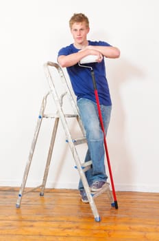 Young man in a T-shirt paints the walls of his first apartment in bright colors.