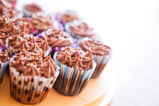 Closeup of chocolate cupcakes with decorative sprinkles on plastic tray