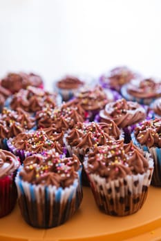 Closeup of chocolate cupcakes with decorative sprinkles on plastic tray