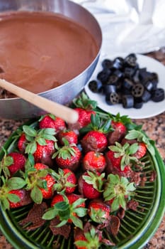 Plate of fresh strawberries and chocolate sauce in pan and licorice pieces