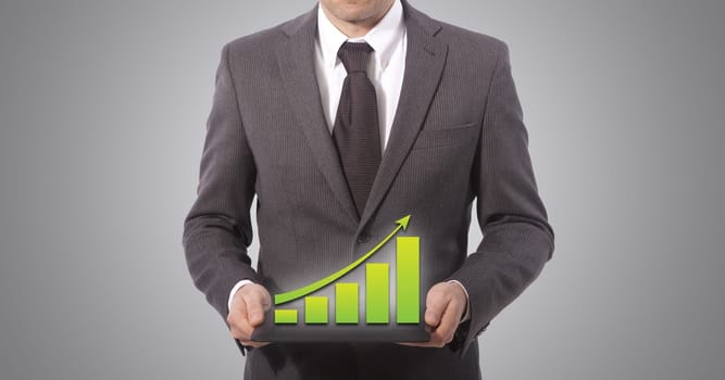 business man with touch screen graph on a tablet, grey background.