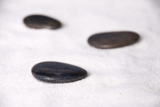 three black stones lying in white sand