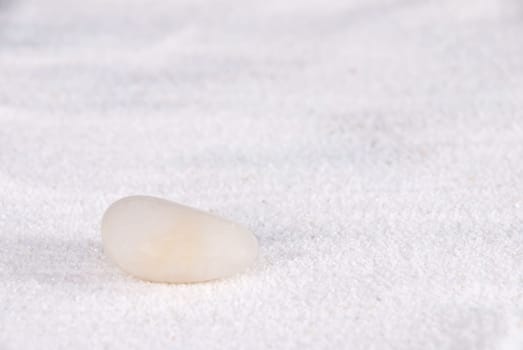 a white stone lying on white sand symbolizing calmness and power