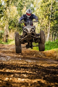 Quad rider jumping on a forest trail.