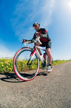 Man on road bike riding down open country road.