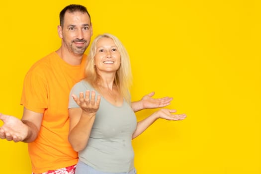 Photo of hesitant married couple looking uncertainly, receiving suggestions, having doubtful facial expressions, isolated over yellow background. Who cares. We do not know.