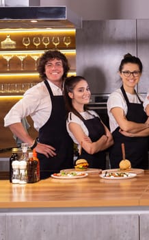 Happy chef and his colleague standing at kitchen and looking at camera - food and restaurant