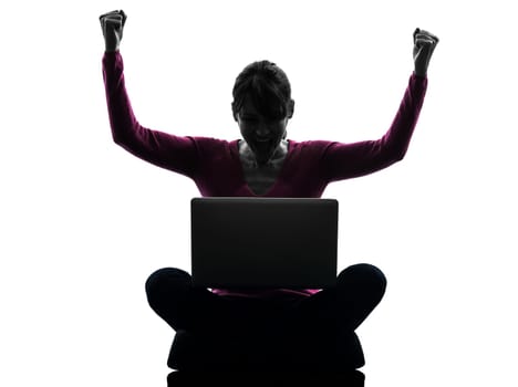 one caucasian woman happy winning  computing laptop computer  in silhouette studio isolated on white background