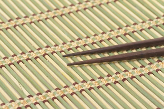 Dark wooden chopsticks on bamboo mat