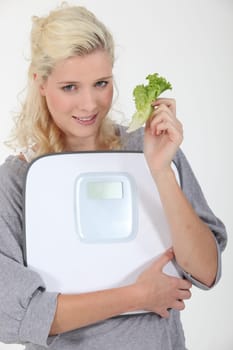 Woman holding lettuce leaf and scales