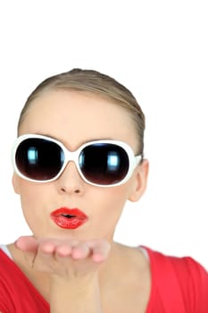 Woman with sunglasses blowing kisses on white background
