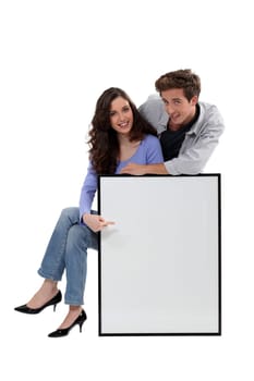 Young couple with a large picture left blank for your message